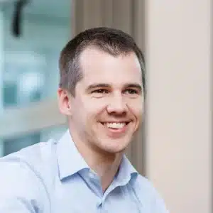 Portrait eines lächelnden Mannes in hellblauem Hemd.